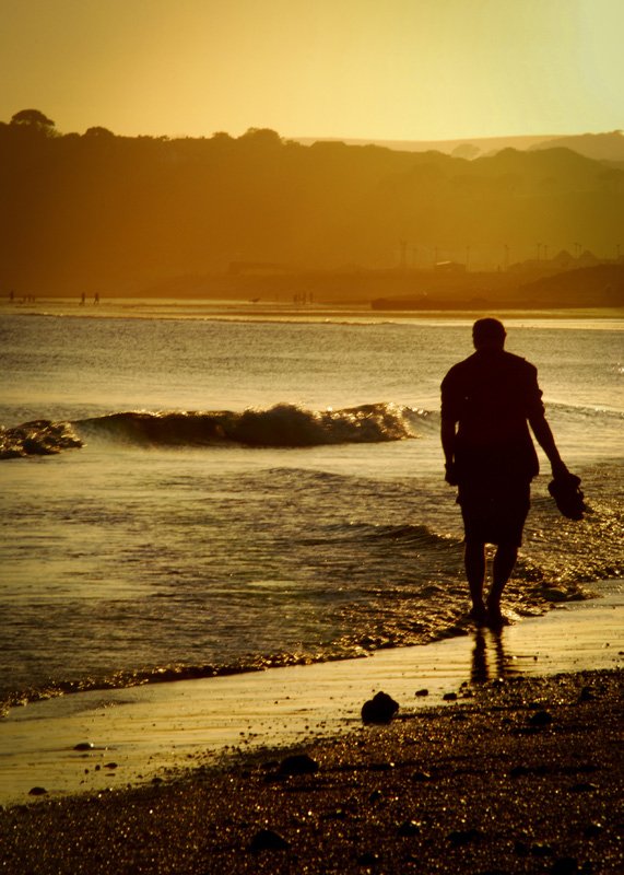 photo-man-walking-on-long-rock-beach